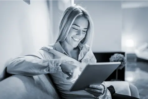 Frau sitzt auf dem Sofa und liest Tablet